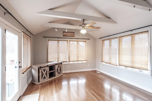 interior space with lofted ceiling with beams, ceiling fan, baseboards, and wood finished floors