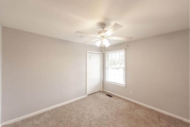 empty room with light carpet, baseboards, visible vents, and a ceiling fan