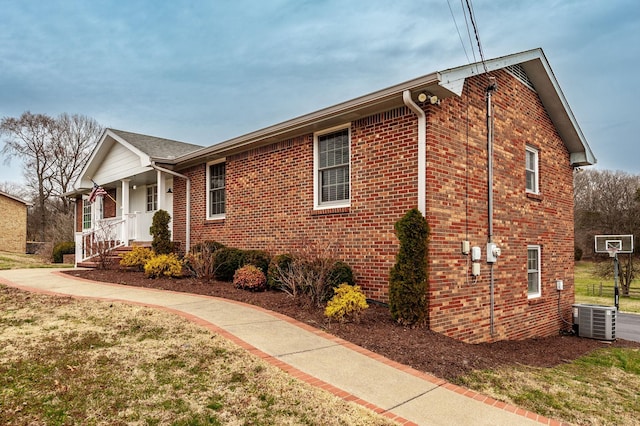 view of home's exterior featuring covered porch, central AC unit, a lawn, and brick siding