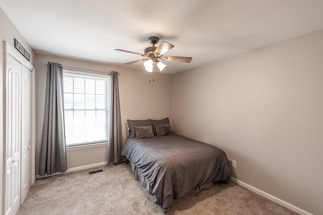 bedroom featuring baseboards, visible vents, a ceiling fan, and light colored carpet