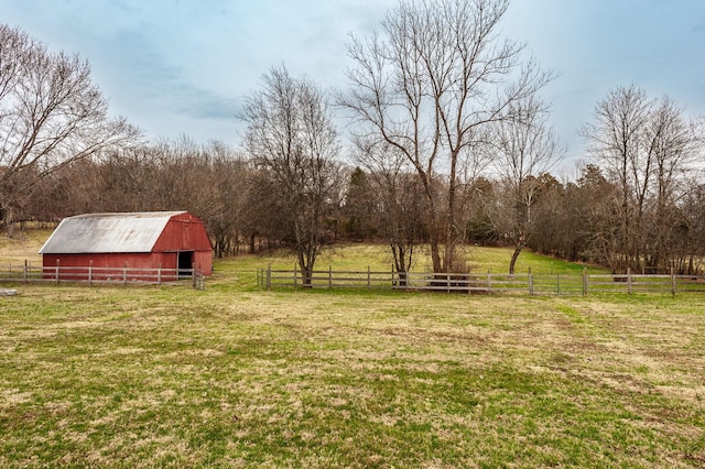 view of yard with a rural view, an outdoor structure, a barn, and fence