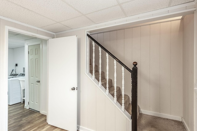 staircase featuring a paneled ceiling, wood finished floors, and independent washer and dryer