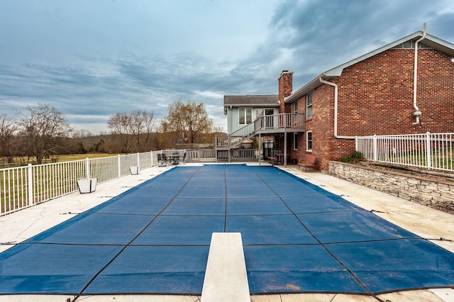 view of pool featuring a diving board, stairway, fence, and a fenced in pool