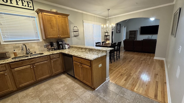 kitchen with arched walkways, dishwasher, brown cabinets, a peninsula, and a sink