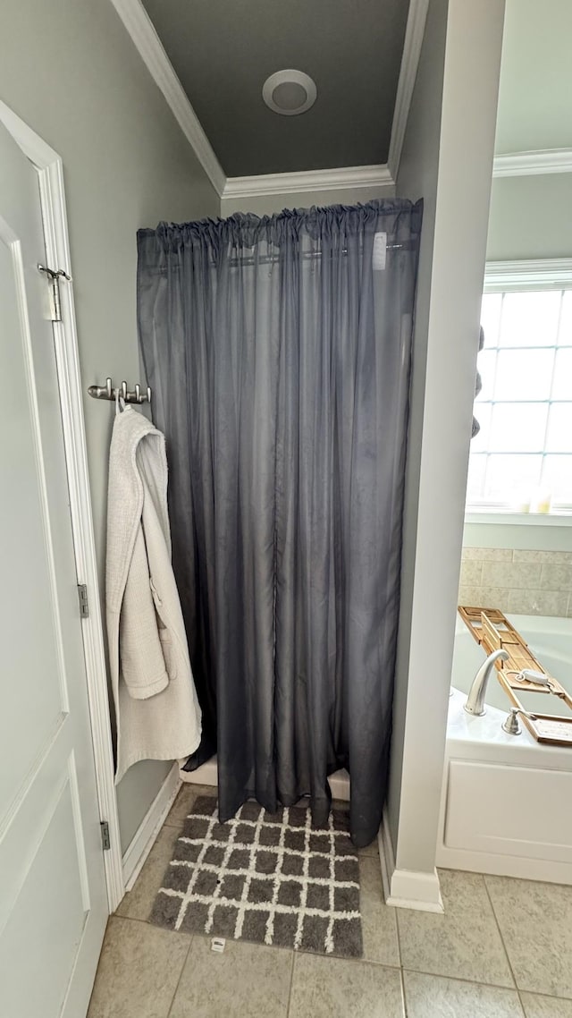 bathroom with a bath, baseboards, crown molding, and tile patterned floors