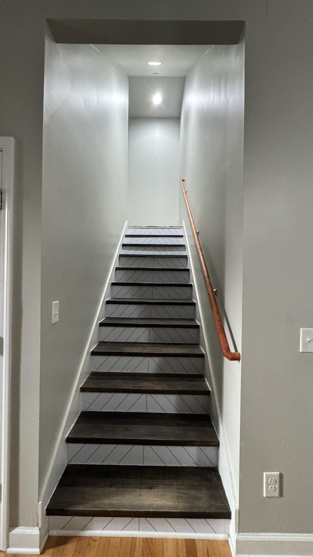 staircase featuring wood finished floors and baseboards