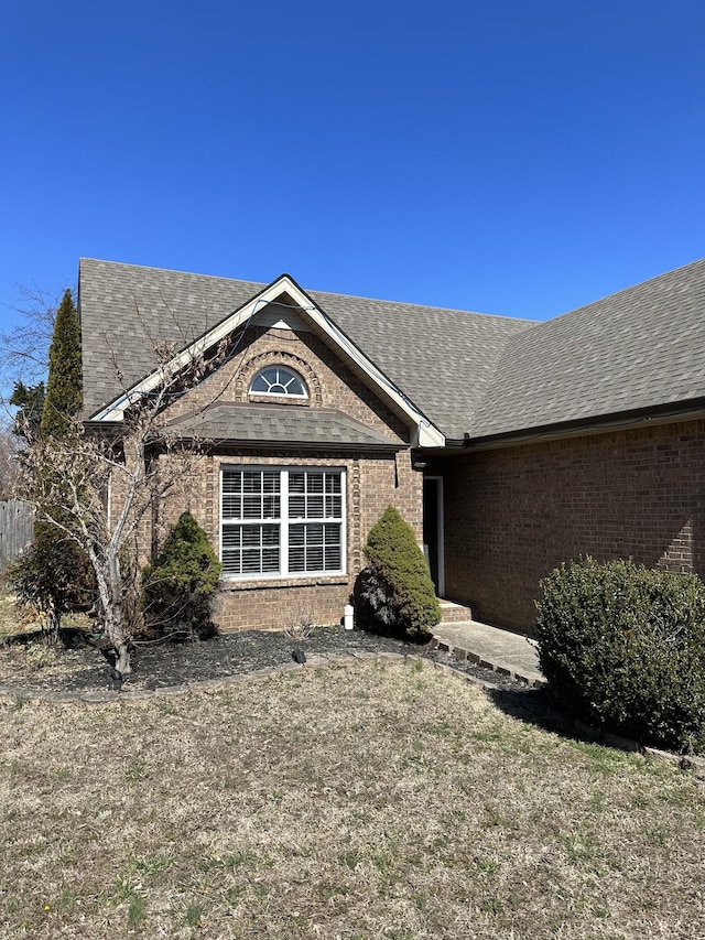 view of front facade with a shingled roof and brick siding