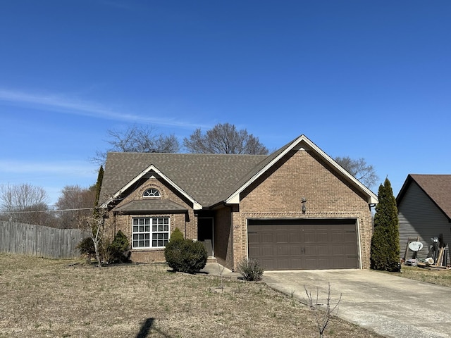 view of front facade featuring roof with shingles, brick siding, an attached garage, fence, and driveway