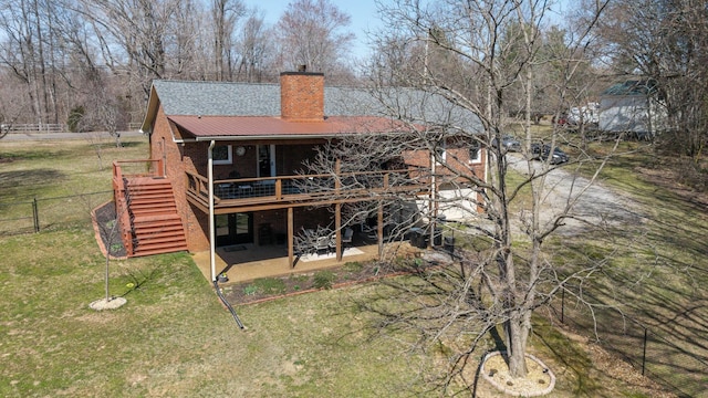 rear view of property with a patio, fence, a deck, a lawn, and metal roof