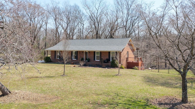 view of front of property with a front lawn, brick siding, covered porch, and roof with shingles