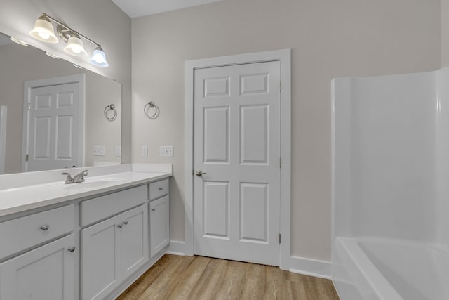 full bath with a tub to relax in, wood finished floors, and vanity