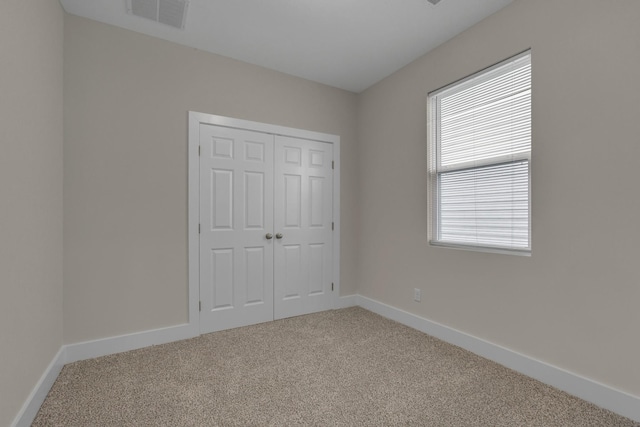 unfurnished bedroom with carpet floors, a closet, visible vents, and baseboards