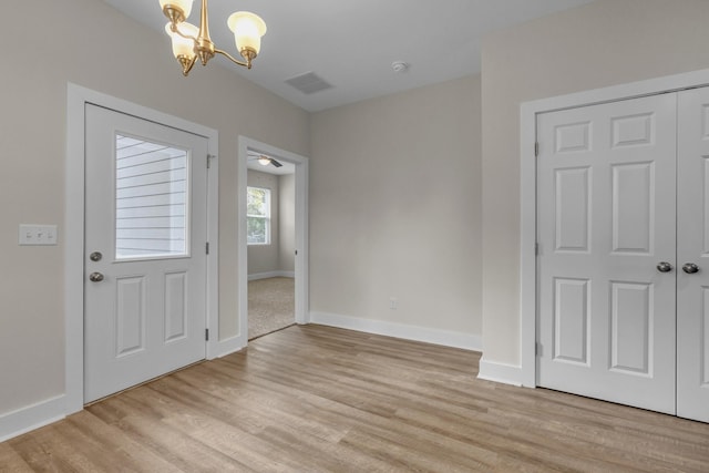 entrance foyer with light wood-type flooring, baseboards, visible vents, and a chandelier