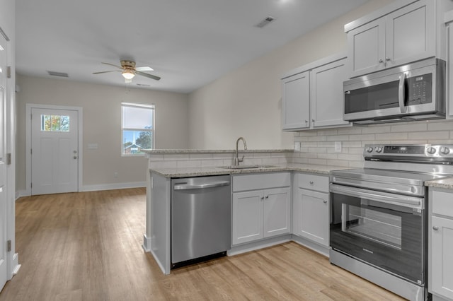 kitchen with appliances with stainless steel finishes, visible vents, a sink, and a peninsula