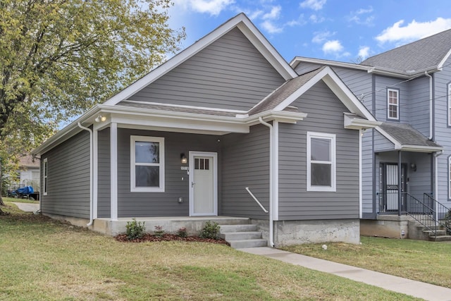 bungalow featuring a shingled roof and a front lawn