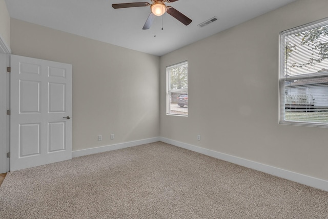 spare room with light carpet, baseboards, visible vents, and a ceiling fan