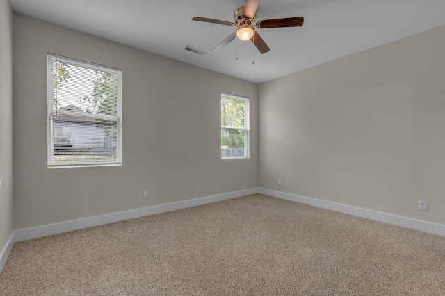 empty room featuring baseboards, visible vents, ceiling fan, and light colored carpet