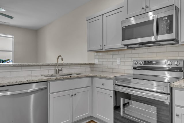 kitchen with tasteful backsplash, visible vents, appliances with stainless steel finishes, light stone counters, and a sink