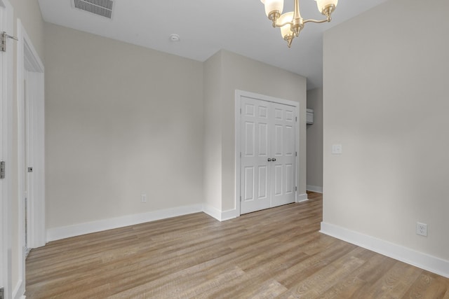 interior space with a notable chandelier, light wood finished floors, a closet, visible vents, and baseboards