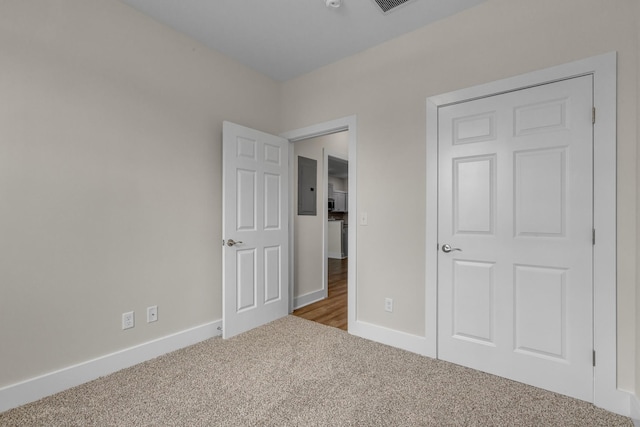 unfurnished bedroom with carpet, electric panel, baseboards, and visible vents