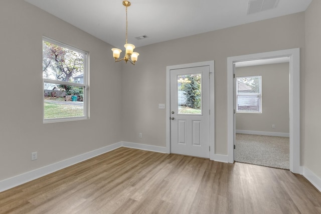 foyer with light wood-style floors, a chandelier, visible vents, and baseboards