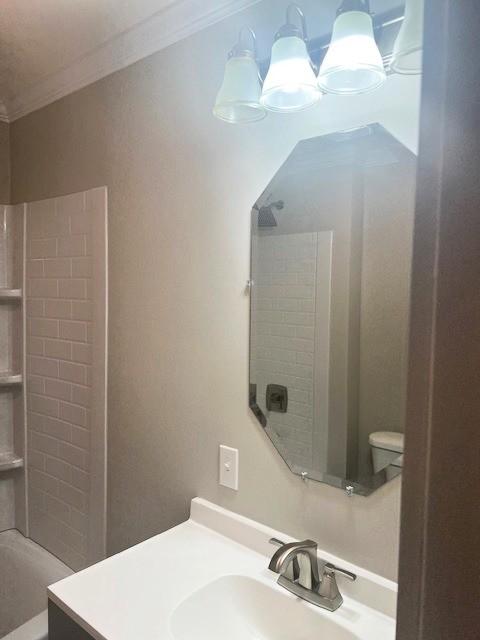 full bathroom with ornamental molding, vanity, and toilet