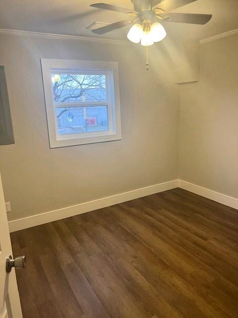 spare room with dark wood-type flooring, crown molding, and baseboards