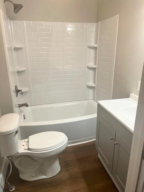 bathroom featuring toilet, vanity, wood finished floors, and shower / bathing tub combination