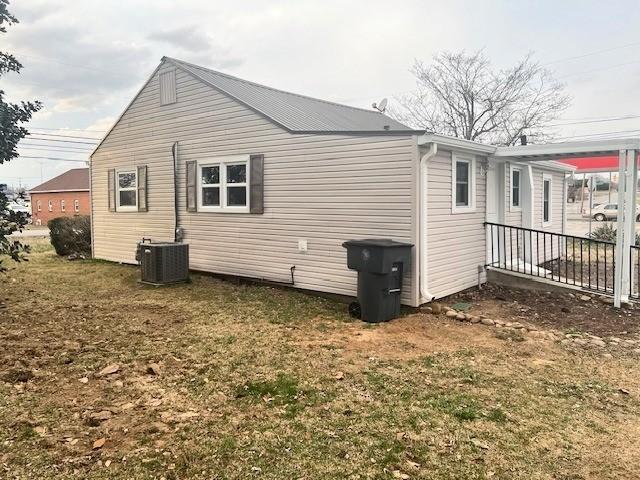 view of side of property featuring central AC and a yard