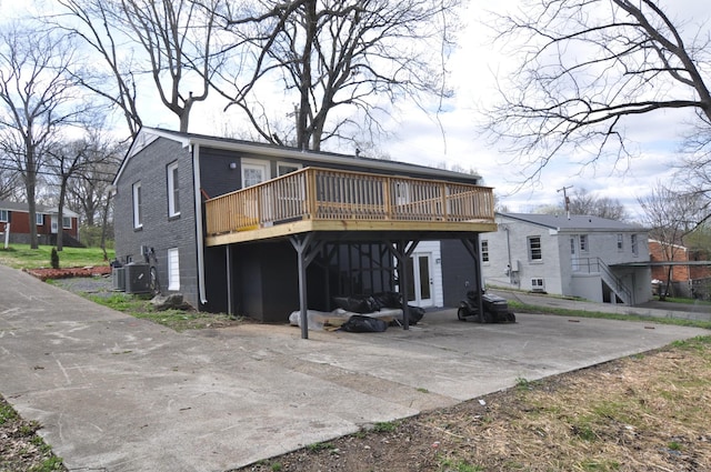 rear view of house with a carport, brick siding, and a wooden deck