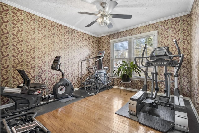 workout area with wallpapered walls, baseboards, ornamental molding, hardwood / wood-style floors, and a textured ceiling