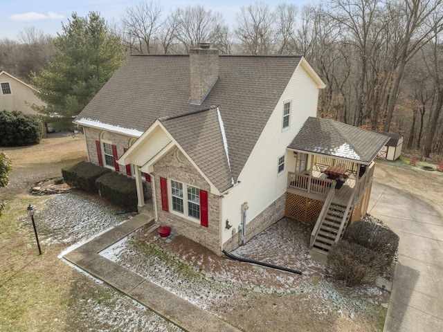 view of front of house with a shingled roof, a chimney, a wooden deck, and stairway