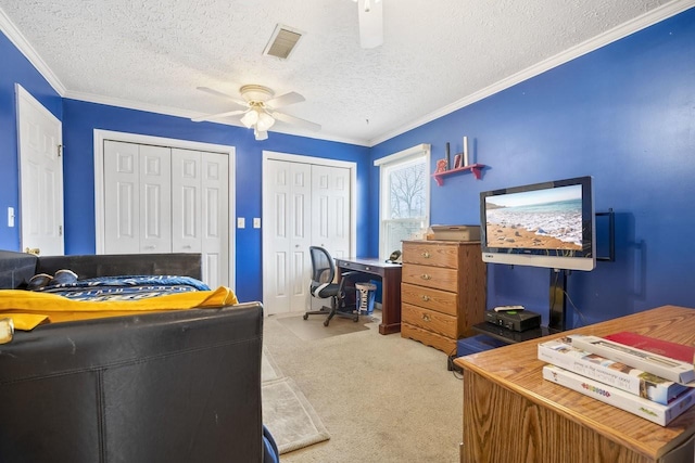 carpeted bedroom with visible vents, a ceiling fan, ornamental molding, a textured ceiling, and two closets