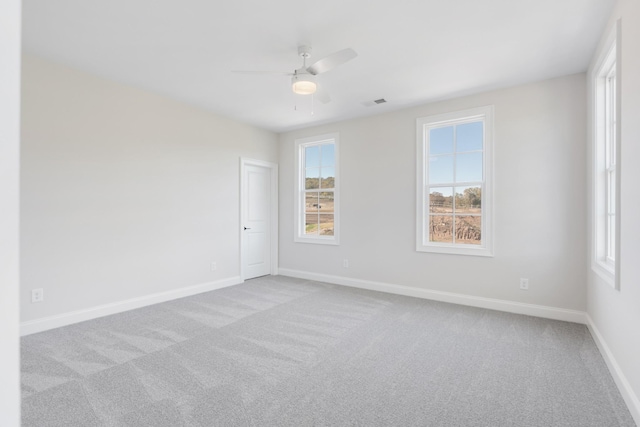 carpeted empty room with visible vents, baseboards, and a ceiling fan