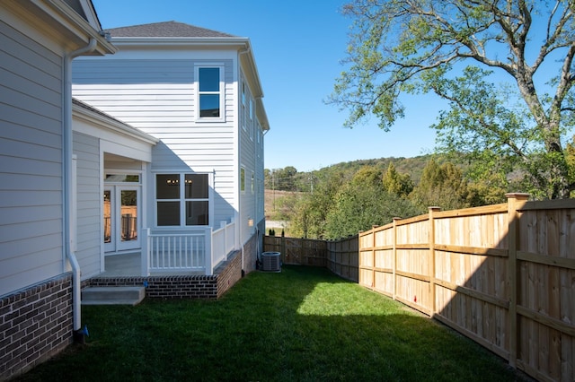 view of yard with central AC, french doors, and a fenced backyard