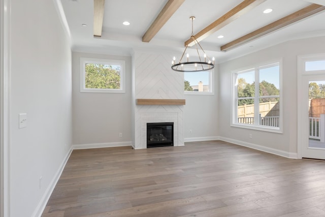 unfurnished living room featuring a large fireplace, beamed ceiling, wood finished floors, and baseboards