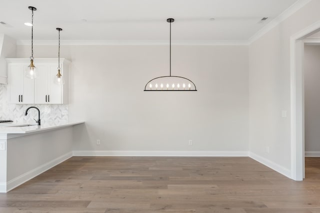 unfurnished dining area with light wood-style floors, a sink, and ornamental molding