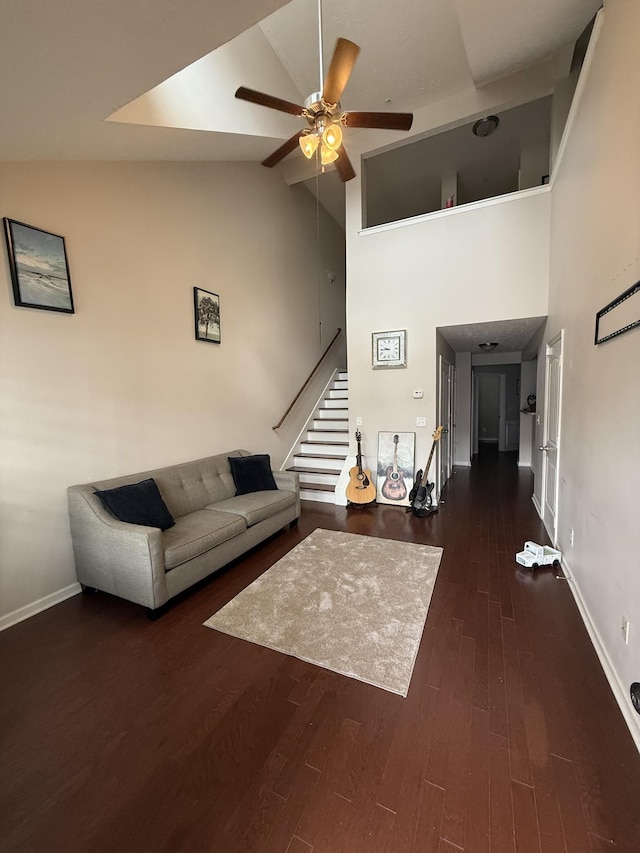 unfurnished living room featuring stairway, a ceiling fan, wood finished floors, high vaulted ceiling, and baseboards