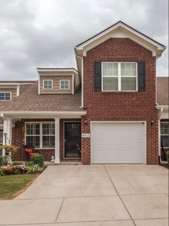 traditional-style home featuring brick siding, an attached garage, concrete driveway, and a shingled roof