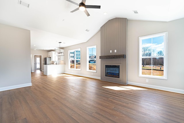 unfurnished living room with visible vents, a large fireplace, plenty of natural light, and dark wood-type flooring