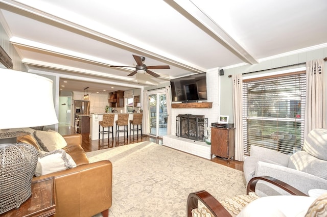 living room featuring a fireplace, wood finished floors, beam ceiling, and crown molding