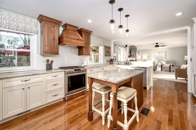 kitchen with visible vents, open floor plan, a peninsula, stainless steel appliances, and light wood-style floors