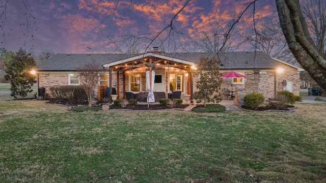 view of front facade with covered porch, a garage, brick siding, a front lawn, and a chimney