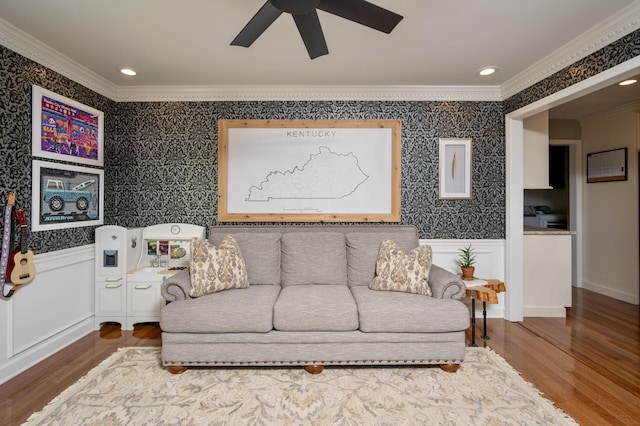 living room with ornamental molding, wood finished floors, wainscoting, and wallpapered walls