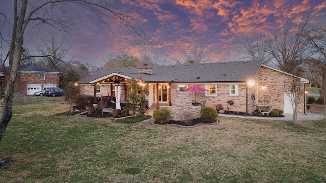 view of front facade featuring a patio, brick siding, a lawn, and a chimney