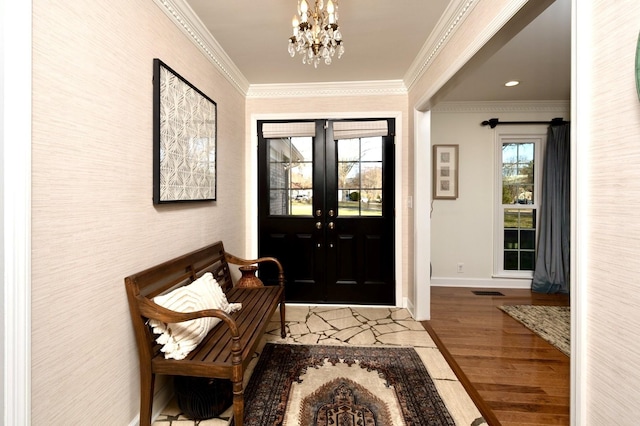 foyer entrance featuring a chandelier, wood finished floors, baseboards, french doors, and ornamental molding