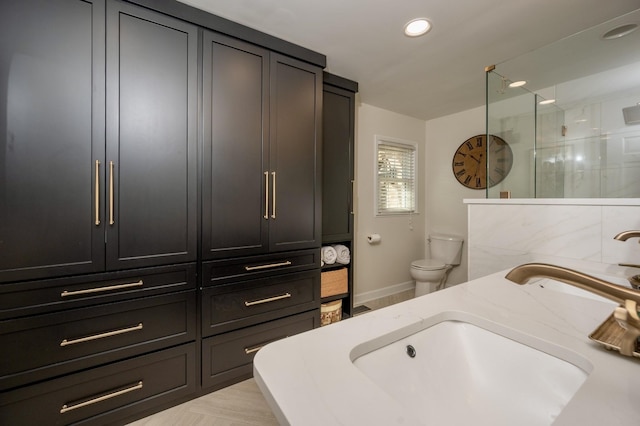 bathroom with recessed lighting, toilet, vanity, baseboards, and walk in shower