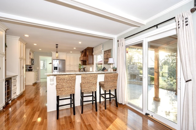 kitchen featuring light wood-type flooring, wine cooler, appliances with stainless steel finishes, and a breakfast bar