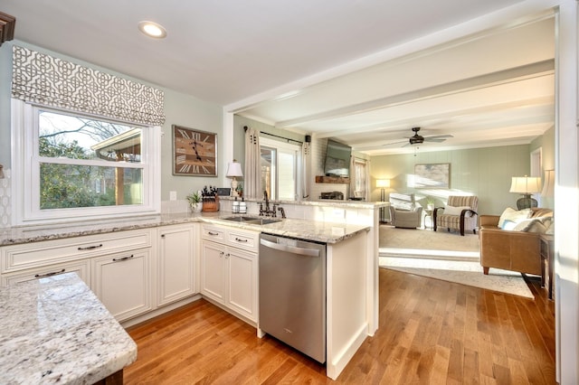 kitchen with light wood finished floors, open floor plan, a peninsula, stainless steel dishwasher, and a sink