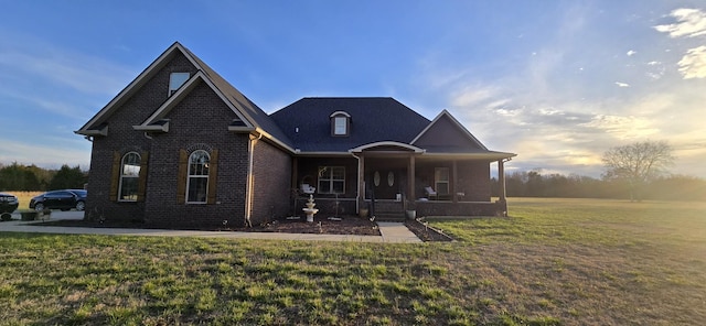 view of front facade with a porch, a front yard, and brick siding